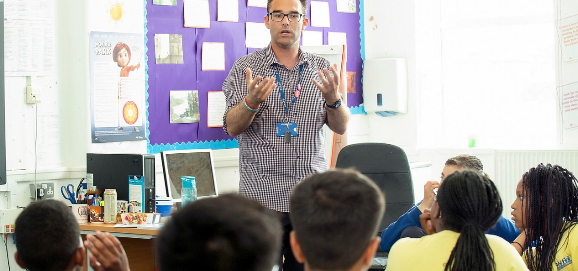 Teacher stood at the front of the class speaking to pupils