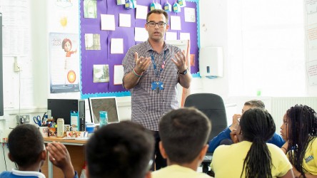 Teacher stood at the front of the class speaking to pupils